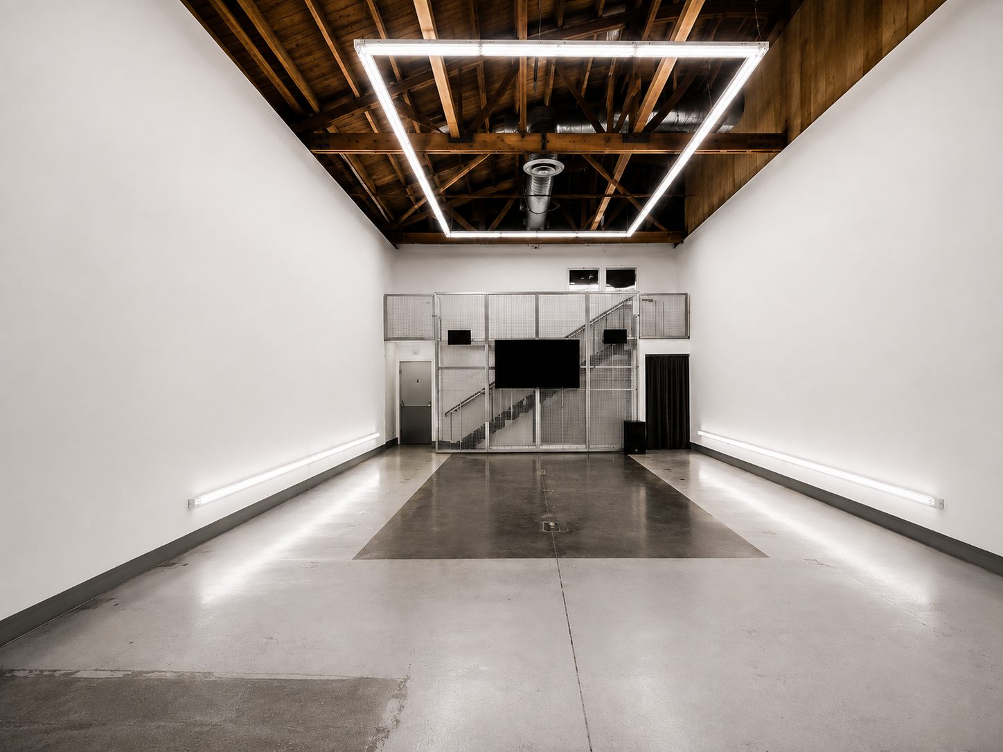 The empty 439 main room — white walls, exposed wood-beam ceiling, concrete floors